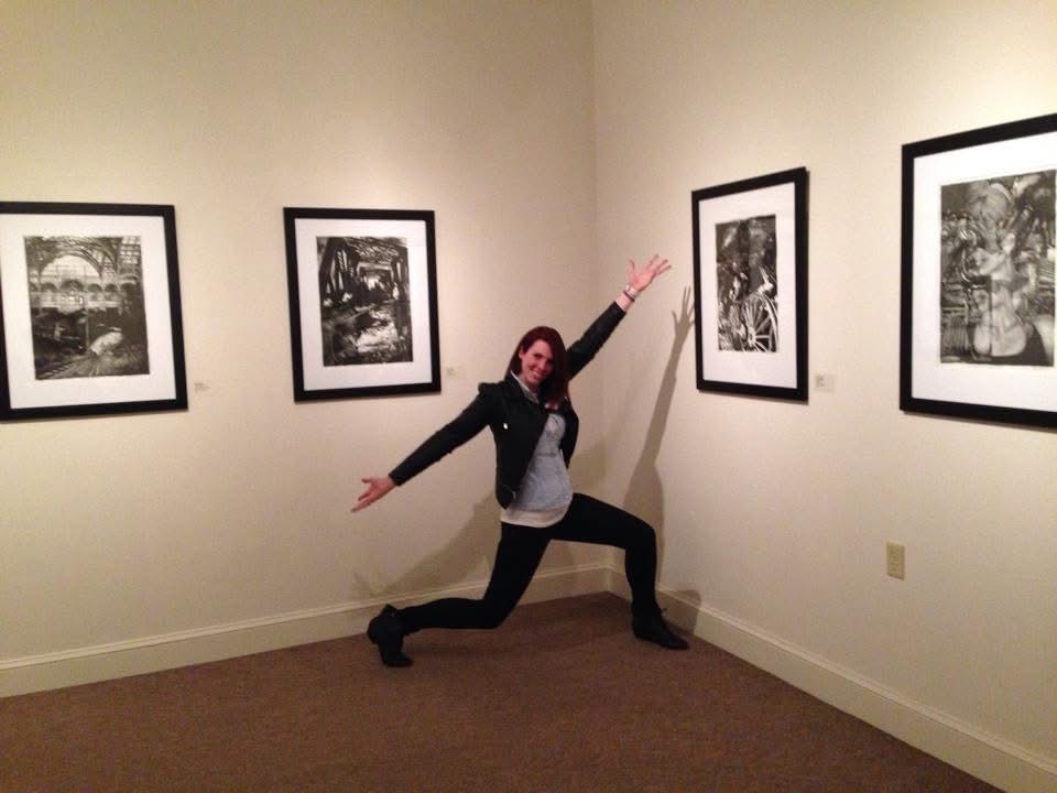 April with arms outstretched in a gallery hung with her prints.