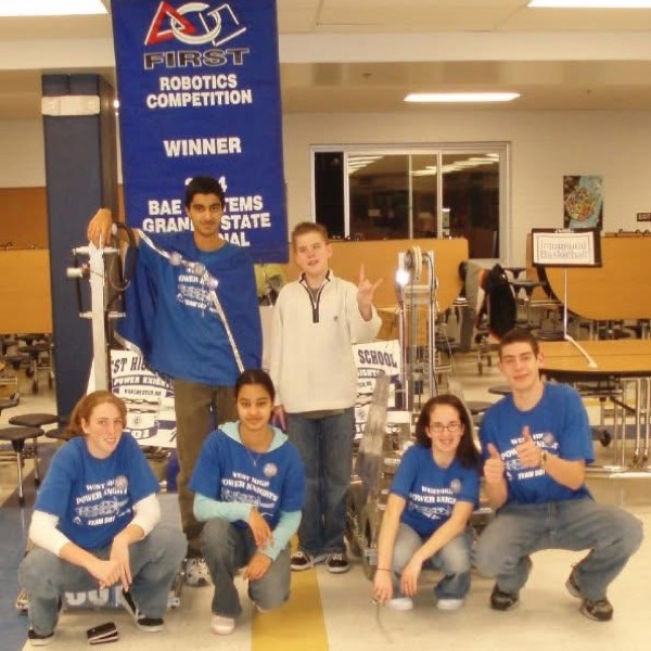 FIRST Robotics team with their competition banner and robot