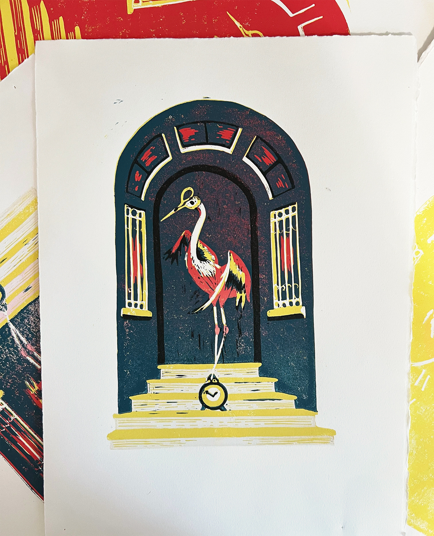 Precarious Flamingo, a reductive linocut. A flamingo with scissor beaks stands atop a mantel clock in a dark blue archway.