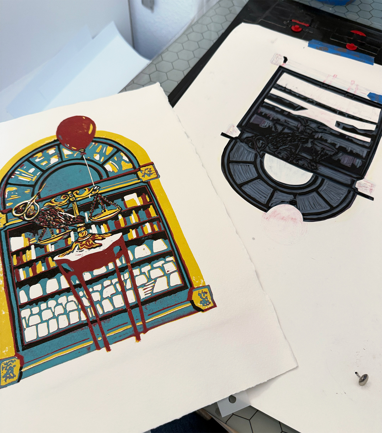 Sunbird Saboteur freshly printed with its black layer, resting on the table beside the carved block for the next piece.